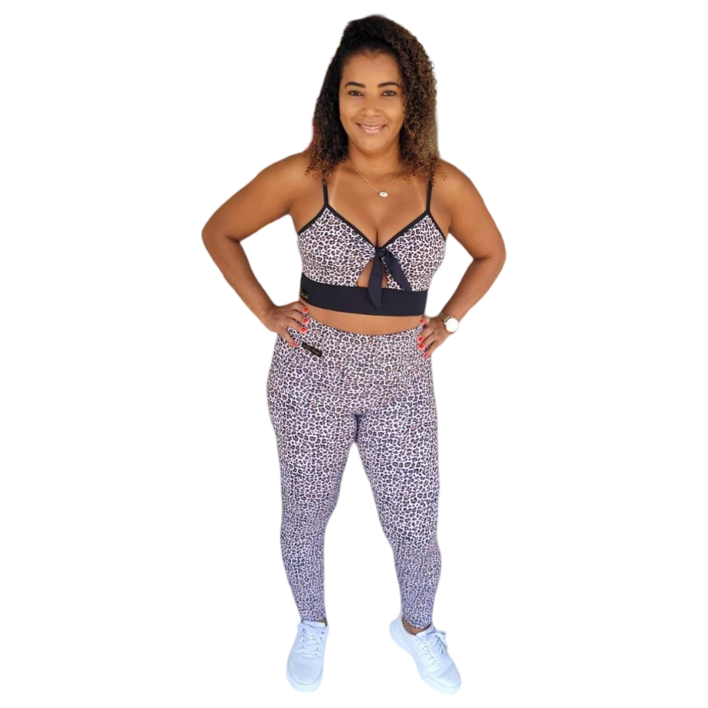 Mulher sorridente usando conjunto fitness com estampa animal print, composto por top com amarração frontal e calça legging, ideal para treinos com conforto e estilo